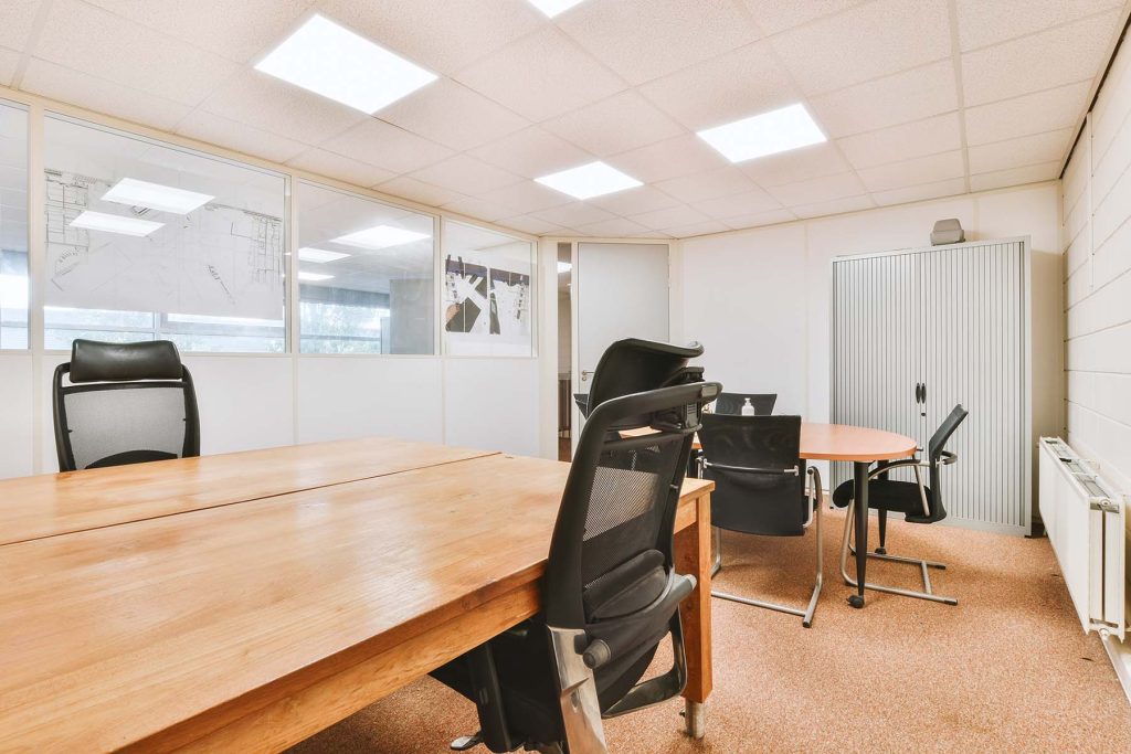 Comfortable chair placed near desk with computer monitors and whiteboard in light workplace in modern apartment